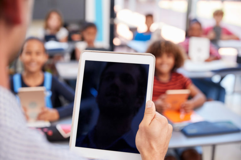 teacher holding tablet in school class over PGZJMCW